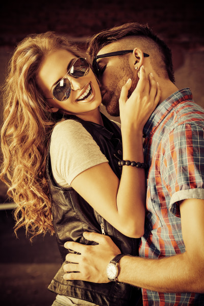 Couple of happy young people in love posing outdoors over brick